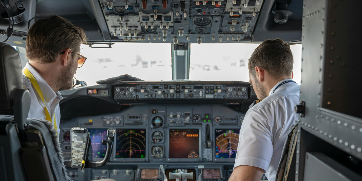 Pilots in a modern aircraft cockpit reviewing safety systems, highlighting the need for updated Safety Risk Management strategies in aviation operations.